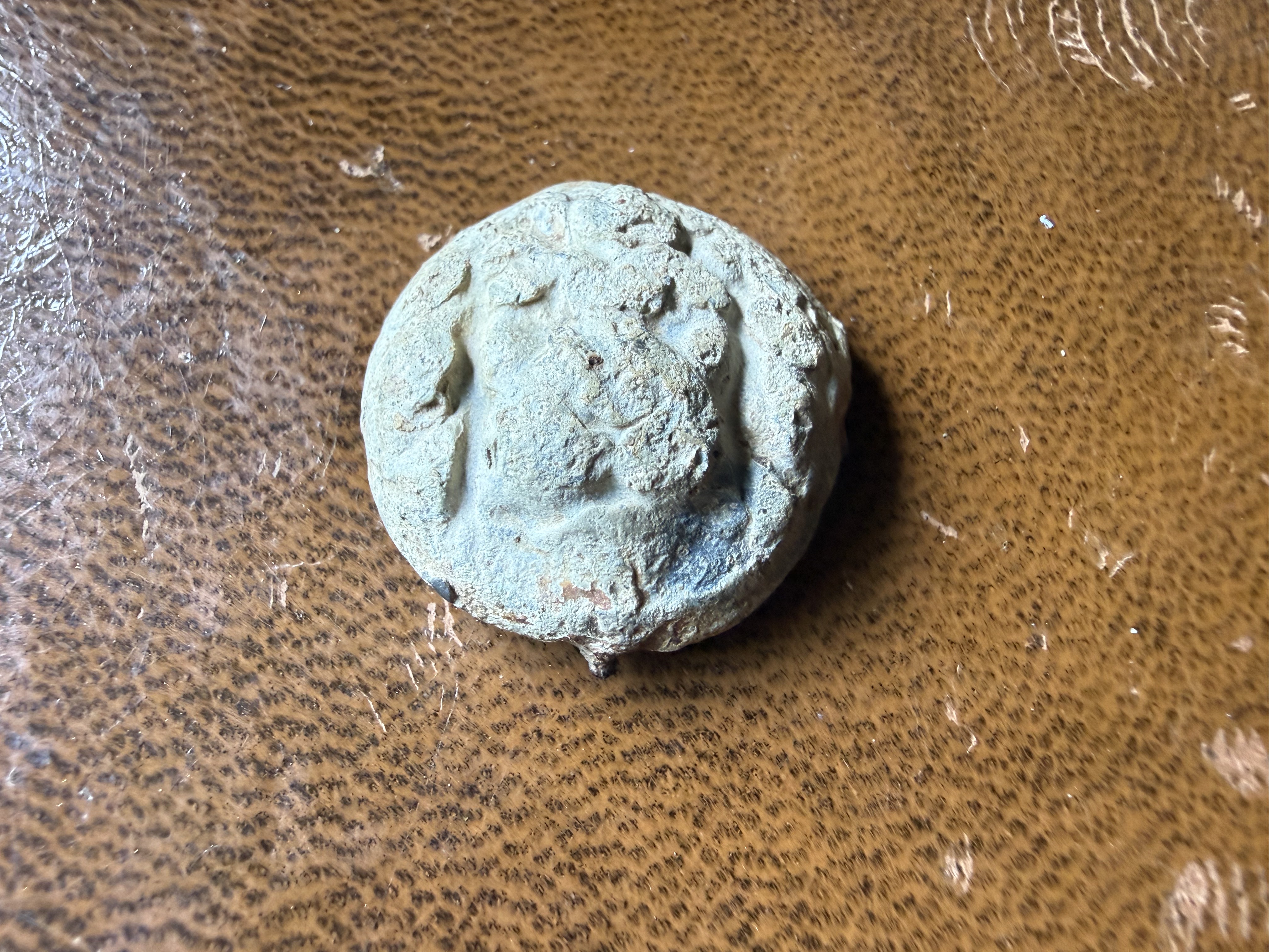 Heavily corroded copper-alloy button with raised decorative face, found by metal detecting